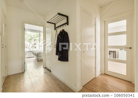 the inside of a house with wood floors and white walls, there is a coat rack hanging on the wall the inside of a house with wood floors and white walls, there is a coat rack hanging on the wall 106050341