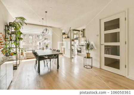 a living room with hardwood flooring and white walls there is a dining table in the room has a tv on the wall a living room with hardwood flooring and white walls there is a dining table in the room has a tv on the wall 106050361