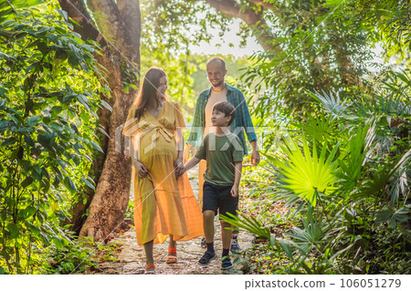 A loving family enjoying a leisurely walk in the park - a radiant pregnant woman after 40, embraced by her husband, and accompanied by their adult teenage son, savoring precious moments together 106051279