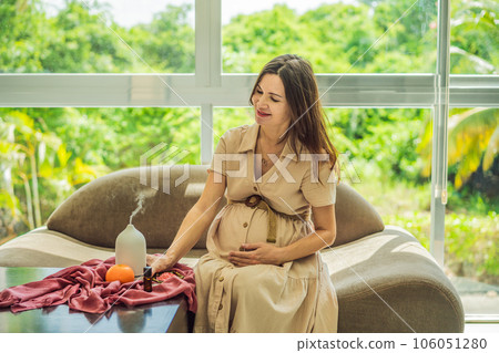 A serene moment captured as a pregnant woman after 40 embraces the soothing benefits of aroma oils and an aroma diffuser, enhancing her pregnancy journey with relaxation and tranquility 106051280