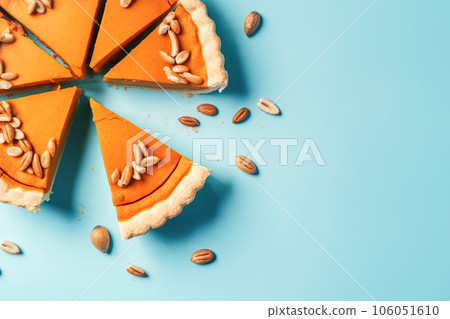 Festive homemade appetizing ripe pumpkin pie, pumpkin tart decorated with nuts, minimalistic blue background with hard shadows, top view. Traditional seasonal fall baking, Thanksgiving 106051610