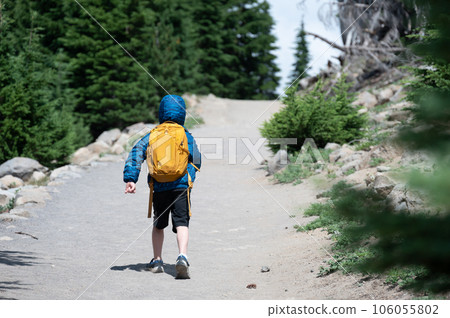 young child wearing a backpack and jacket on a hike up a dusty trail. young child wearing a backpack and jacket on a hike up a dusty trail. 106055802