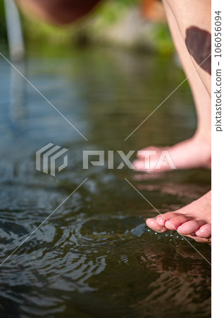 Caucasian child dipping toes into a cold snowmelt mountain stream on a sunny day 106056094