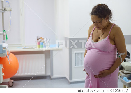 Pregnant woman birthing mother with painful contraction, touching belly and looking down. Childbirth process at hospital Pregnant woman birthing mother with painful contraction, touching belly and looking down. Childbirth process at hospital 106056522