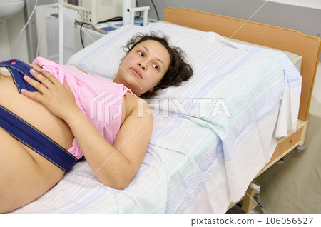 Pregnant woman in hospital and fetal heartbeat monitor. Labor process. Birthing mother having painful contractions Pregnant woman in hospital and fetal heartbeat monitor. Labor process. Birthing mother having painful contractions 106056527