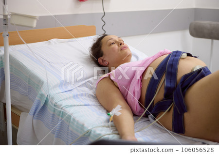 Pregnant birthing mother woman has contractions, checks the heartbeat and pulse of her baby, using an electrocardiogram 106056528