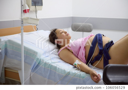 Birthing mother with a belt around her belly checking the heartbeat and pulse of future baby, during the labor process Birthing mother with a belt around her belly checking the heartbeat and pulse of future baby, during the labor process 106056529