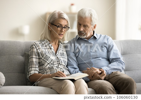 Caring senior wife reading book aloud to older husband Caring senior wife reading book aloud to older husband 106060130