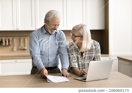 Cheerful retired husband and wife checking financial paper document Cheerful retired husband and wife checking financial paper document 106060173