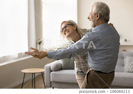 Joyful older retired husband and wife dancing to music 106060213