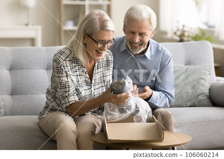 Cheerful senior online store customers couple opening parcel from webstore Cheerful senior online store customers couple opening parcel from webstore 106060214
