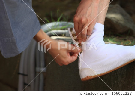 A mikoshi bearer tightening the kohaze of the festival tabi 106061228