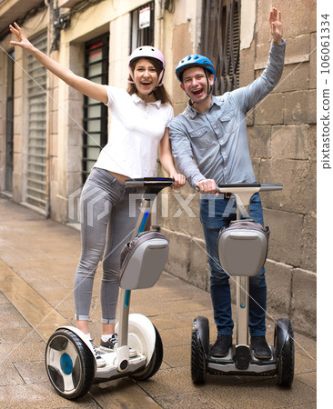 Young couple guy and girl walking on segway in streets of european city 106061334