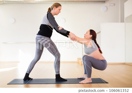 Pregnant woman does yoga with an instructor 106061352