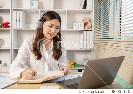Beautiful young asian woman watching live video or video call of teacher teaching on laptop in her home, Take notes of important conversations and messages during the teacher's teaching. Beautiful young asian woman watching live video or video call of teacher teaching on laptop in her home, Take notes of important conversations and messages during the teacher's teaching. 106061398