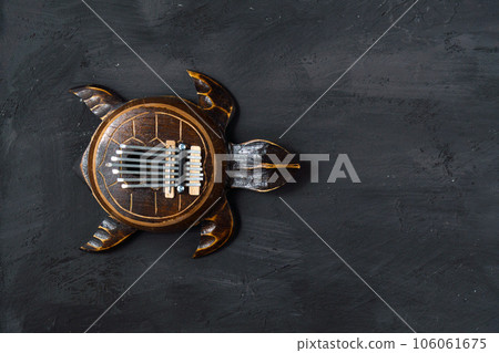 Kalimba turtle on a black background. Traditional musical instrument. Folk music or meditative music concept. Copy space 106061675