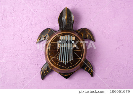 Kalimba turtle on a purple background. Traditional musical instrument. Folk music or meditative music concept Kalimba turtle on a purple background. Traditional musical instrument. Folk music or meditative music concept 106061679