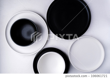 Empty ceramic plate, black and white on a concrete white background. Stylish tableware Empty ceramic plate, black and white on a concrete white background. Stylish tableware 106061721