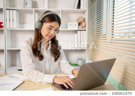 Woman using laptop to work or do homework at home with smiling face in her office, Creating happiness at work with a smile, Live performance or vdo call with laptop, Work from home. Woman using laptop to work or do homework at home with smiling face in her office, Creating happiness at work with a smile, Live performance or vdo call with laptop, Work from home. 106061870