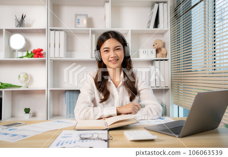 Woman using laptop to work or do homework at home with smiling face in her office, Creating happiness at work with a smile, Live performance or vdo call with laptop, Work from home. Woman using laptop to work or do homework at home with smiling face in her office, Creating happiness at work with a smile, Live performance or vdo call with laptop, Work from home. 106063539
