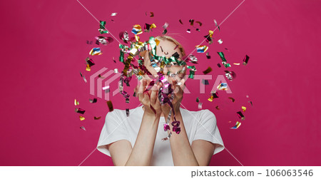 Confetti. Pretty woman blowing confetti on vivid pink background 106063546