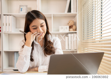 Woman using laptop to work or do homework at home with smiling face in her office, Creating happiness at work with a smile, Live performance or vdo call with laptop, Work from home. Woman using laptop to work or do homework at home with smiling face in her office, Creating happiness at work with a smile, Live performance or vdo call with laptop, Work from home. 106063802