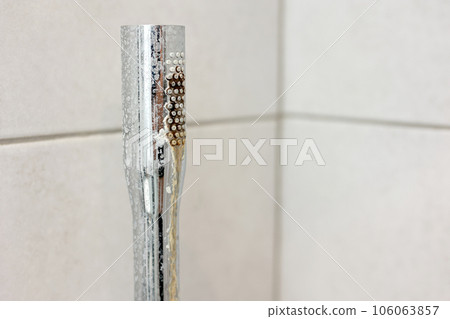 Dirty calcified shower chrome mixer tap, faucet with limescale on it, plaque from hard water. Steel plumbing with fungus, mildew, close up. Bathroom with grey tiles interior. Domestic life concept 106063857