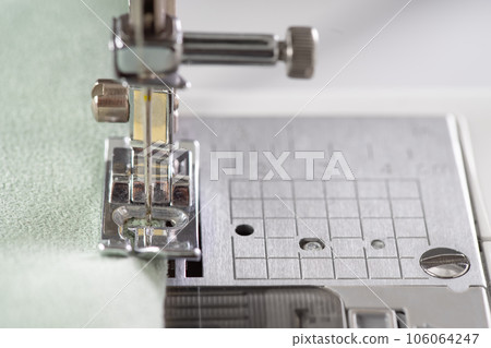 Modern sewing machine presser foot with green fabric and thread, closeup, macro Modern sewing machine presser foot with green fabric and thread, closeup, macro 106064247