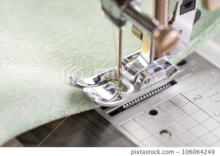 Modern sewing machine presser foot with green fabric and thread, closeup, macro Modern sewing machine presser foot with green fabric and thread, closeup, macro 106064249