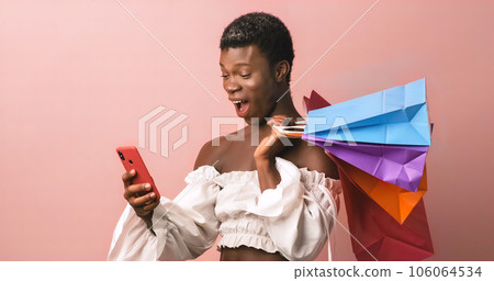 African transgender person using mobile phone while holding shopping bags. African transgender person using mobile phone while holding shopping bags. 106064534