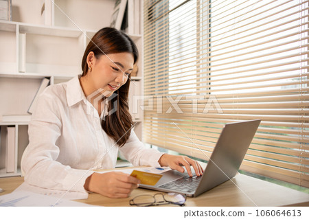 Woman's finger presses a keyboard and holds a credit card to register for payment or online transactions, Financial transactions and Internet security, Shopping online and banking online concept. Woman's finger presses a keyboard and holds a credit card to register for payment or online transactions, Financial transactions and Internet security, Shopping online and banking online concept. 106064613