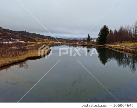 River flow in icelandic national park with arctic nature forming beautiful landscape, tourist attraction. Scenic route in iceland with massive water stream near frozen meadows, golden circle. River flow in icelandic national park with arctic nature forming beautiful landscape, tourist attraction. Scenic route in iceland with massive water stream near frozen meadows, golden circle. 106064645