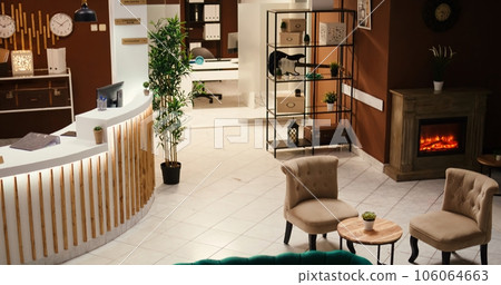 Tilt down shot of posh green sofa and armchairs furniture in empty luxury hotel foyer interior with ready to welcome tourists. Stylish travel vacation accommodation lounge with check in reception Tilt down shot of posh green sofa and armchairs furniture in empty luxury hotel foyer interior with ready to welcome tourists. Stylish travel vacation accommodation lounge with check in reception 106064663