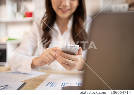 Young women use smartphones to play games or watch video clips to relax after a break from completing homework. Use mobile phones to create entertainment and happiness. 106064714