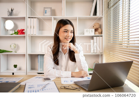Woman using laptop to work or do homework at home with smiling face in her office, Creating happiness at work with a smile, Live performance or vdo call with laptop, Work from home. Woman using laptop to work or do homework at home with smiling face in her office, Creating happiness at work with a smile, Live performance or vdo call with laptop, Work from home. 106064720