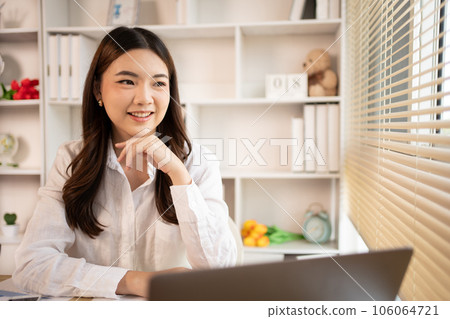 Woman using laptop to work or do homework at home with smiling face in her office, Creating happiness at work with a smile, Live performance or vdo call with laptop, Work from home. Woman using laptop to work or do homework at home with smiling face in her office, Creating happiness at work with a smile, Live performance or vdo call with laptop, Work from home. 106064721