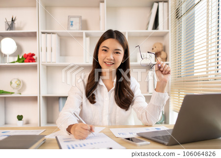 Woman using laptop to work or do homework at home with smiling face in her office, Creating happiness at work with a smile, Live performance or vdo call with laptop, Work from home. 106064826