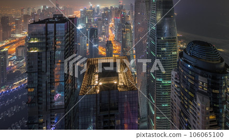 Skyline panoramic view of Dubai Marina showing canal surrounded by skyscrapers along shoreline all night timelapse. DUBAI, UAE 106065100