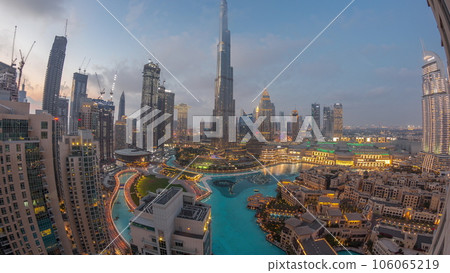 Skyscrapers rising above Dubai downtown day to night timelapse surrounded by modern buildings aerial top view Skyscrapers rising above Dubai downtown day to night timelapse surrounded by modern buildings aerial top view 106065219