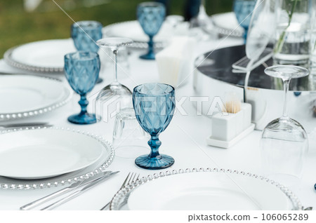 Open -air wedding banquet. The table is decorated with white plates and premium glasses for wine 106065289