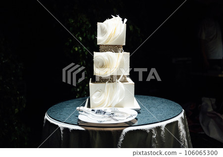 Premium square form wedding cake three floors at the evening ceremony 106065300