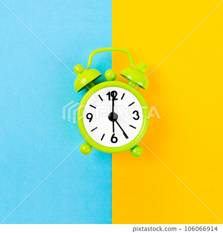 The Green color alarm clock at center on yellow and blue background. The Green color alarm clock at center on yellow and blue background. 106066914