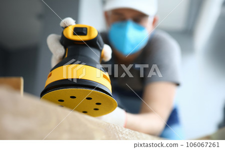 Male handy man hold yellow grinder with disc sander in hand closeup Male handy man hold yellow grinder with disc sander in hand closeup 106067261