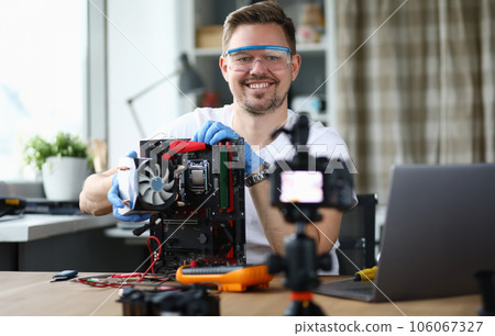 Man sits at table and repairs computer processor 106067327