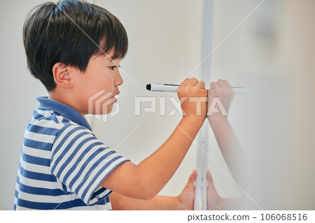 Elementary school boy writing answers on the whiteboard 106068516
