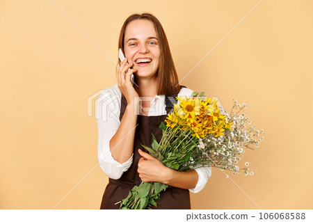 Taking order woman florist wearing brown apron to arrange bouquet in design store, happy smiling young lady making embracing beautiful flowers. Taking order woman florist wearing brown apron to arrange bouquet in design store, happy smiling young lady making embracing beautiful flowers. 106068588