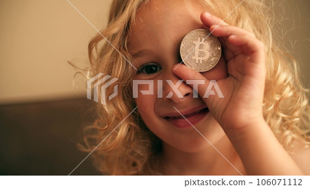 Little girl plays with a BTC bitcoin token or coin 106071112