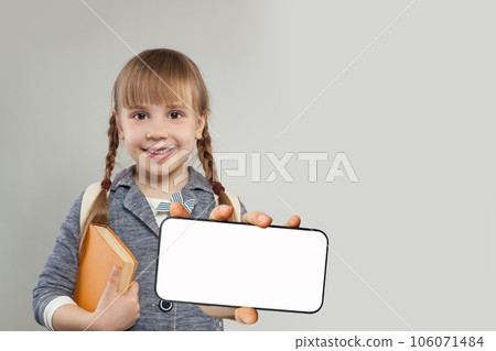 Pretty smiling child school student with blank empty white screen display on smartphone.  106071484