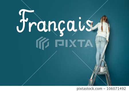 Child student girl standing on ladder and writing French language on blue chalkboard 106071492