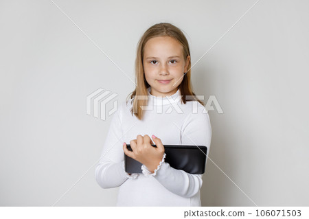Attractive happy young girl using modern tablet gadget against white studio wall background Attractive happy young girl using modern tablet gadget against white studio wall background 106071503